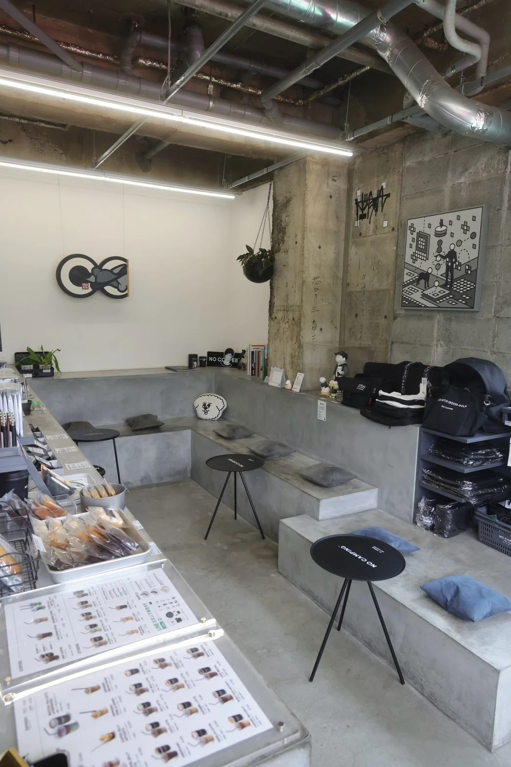 NO COFFEE 平尾本店の店内。コンクリートのベンチと壁面のアート、オリジナルグッズ。