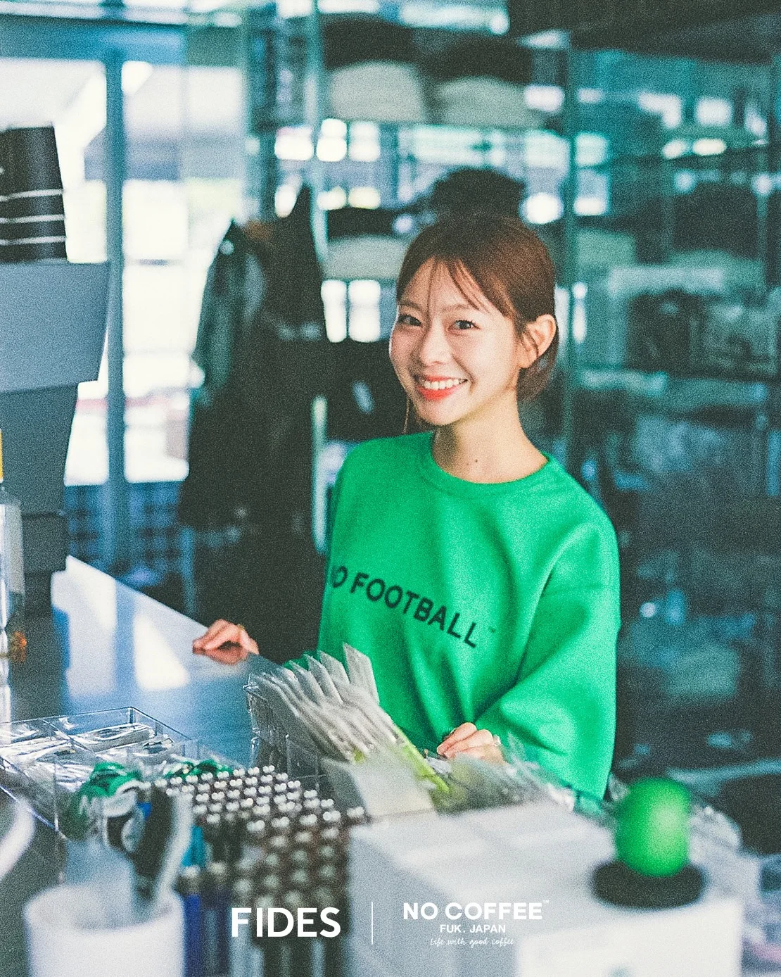 ライトグリーンのスウェットを着用し店内に立つモデル。